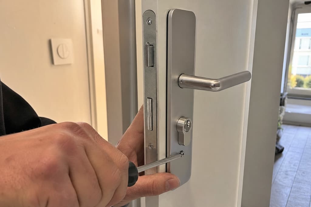 Pose serrure sécurité porte intérieure mains serrant vis